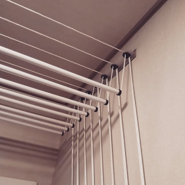 Detalhe das varetas e das roldanas de um varal de teto junto à parede
